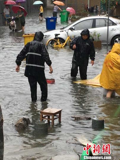 大雨中，城管队员帮助市民寻找积水中的漂浮物。　城管供图　摄