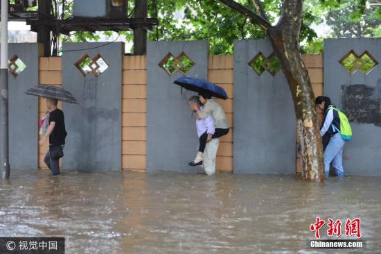 资料图：6月10日，南京市雨花台区，市民在水中艰难出行。图片来源：视觉中国